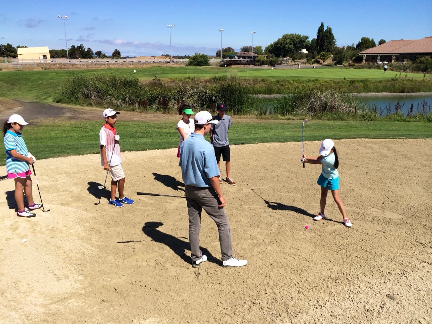 An SV Golf coach working with a camper in a practice bunker